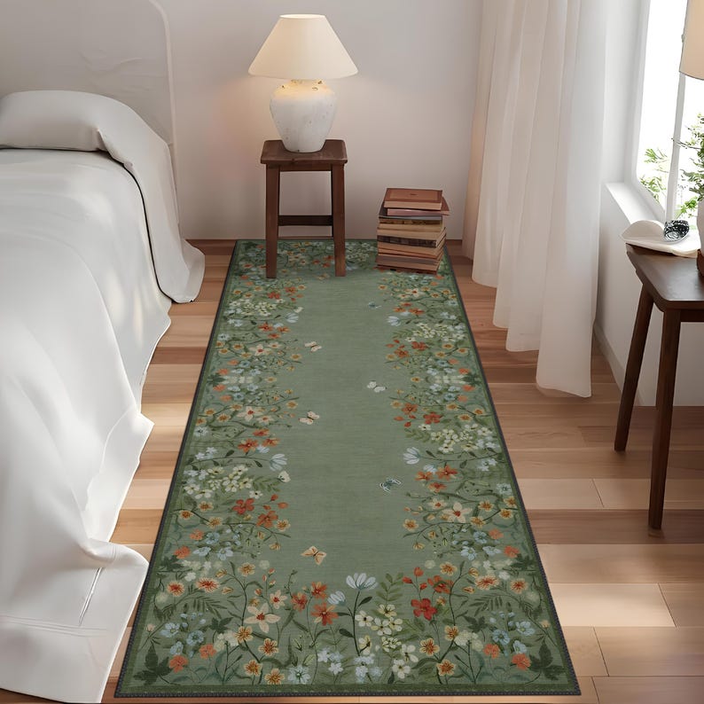 Peut inclure: Un tapis de couloir floral vert avec un fond vert clair et une bordure de fleurs blanches, orange et vertes. Le tapis est plac&eacute; sur un sol en bois dans une pi&egrave;ce avec un lit blanc et une table d'appoint avec une lampe.