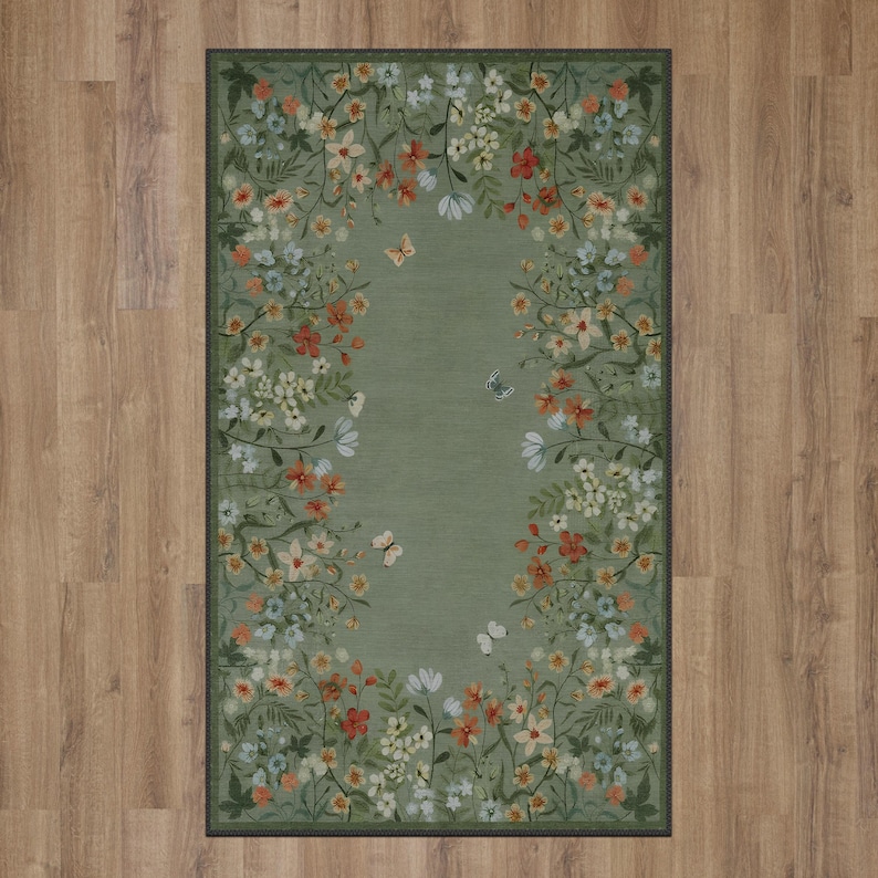 Peut inclure: Un tapis vert avec une bordure florale repr&eacute;sentant une vari&eacute;t&eacute; de fleurs et de papillons. Le tapis a un fond vert clair avec une bordure vert fonc&eacute;.