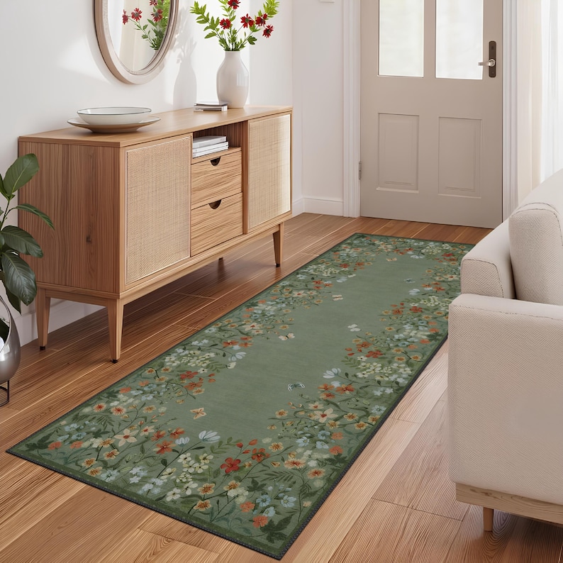 Peut inclure: Un tapis de couloir vert &agrave; fleurs avec une bordure noire. Le tapis a un fond vert clair avec un motif floral dans les tons de rouge, orange, blanc et bleu. Le tapis est plac&eacute; dans un couloir avec un sol en bois et un meuble en bois.