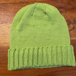 Puede incluir: Un gorro de punto verde lima con un borde doblado.