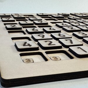 May include: A wooden game board with a grid of numbered squares. The numbers 1 through 9 are visible on the squares.