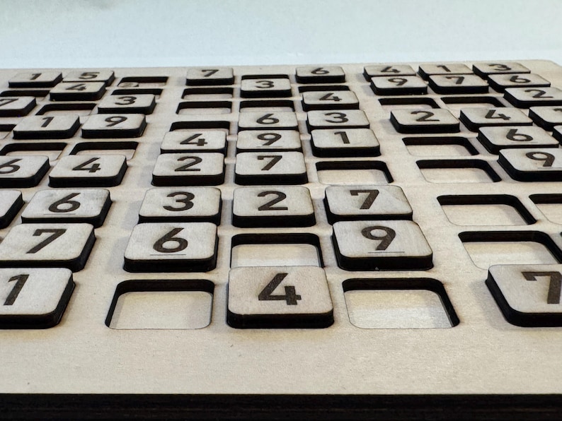 May include: A wooden game board with a grid of squares, each containing a number from 1 to 9. The board is made of light brown wood and has a natural finish.