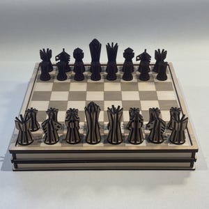 Pode incluir: Um jogo de xadrez de madeira com peças pretas e brancas em um tabuleiro de madeira. As peças estão todas em suas posições iniciais.
