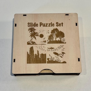 Może przedstawiać: Drewniane pudełko z wygrawerowanym napisem "Slide Puzzle Set" na przodzie. Pudełko zawiera cztery różne obrazy: palmę, panoramę miasta, rekina i nurka.