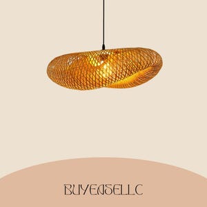 May include: A woven, oval-shaped pendant light fixture. The light is made of a golden-brown material, with a lattice design that allows light to filter through. The fixture hangs from a black cord against a neutral background. The text "BUYENSELLC" is at the bottom.