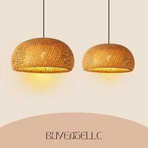 May include: Two woven bamboo pendant lights with a warm, golden glow. The lamps have a dome shape and are suspended from black cords. The lamps are lit from within, casting a soft light. The text "BUYENSELLC" is at the bottom.