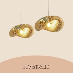May include: Two pendant lights with a woven, shell-like design. The lamps are made of a light brown material and have a warm, inviting glow from the light source within. The lamps are suspended from black cords against a neutral background.
