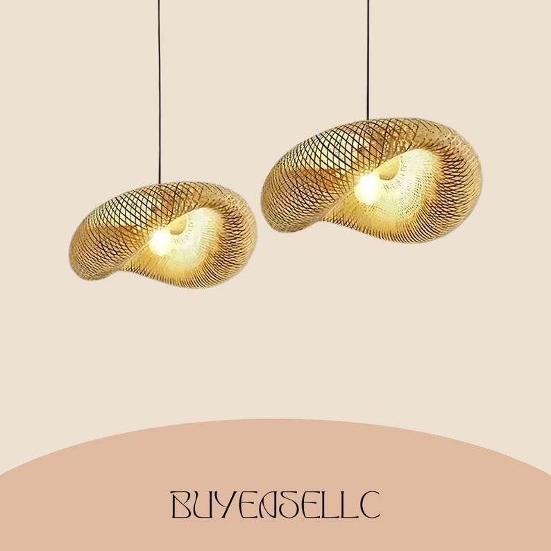 May include: Two pendant lights with a woven, shell-like design. The lamps are made of a light brown material and have a warm, inviting glow from the light source within. The lamps are suspended from black cords against a neutral background.