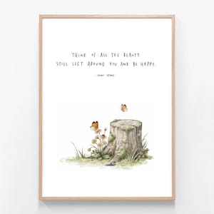 May include: A framed wall art print featuring a tree stump with moss, small white flowers, and two orange butterflies. The text reads: THINK OF ALL THE BEAUTY STILL LEFT AROUND YOU AND BE HAPPY. - ANNE FRANK. The frame is light-coloured wood.