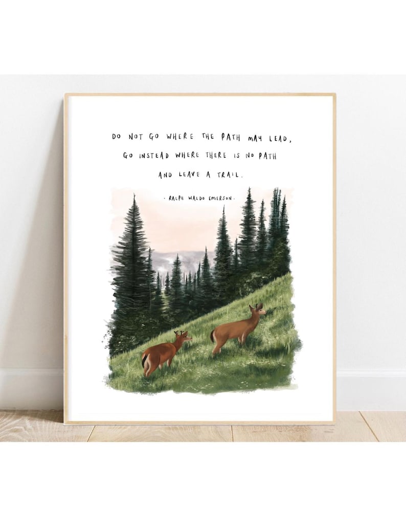 May include: A framed art print featuring a watercolor illustration of two deer on a grassy hillside with evergreen trees. The print includes the quote "DO NOT GO WHERE THE PATH MAY LEAD, GO INSTEAD WHERE THERE IS NO PATH AND LEAVE A TRAIL." by Ralph Waldo Emerson.