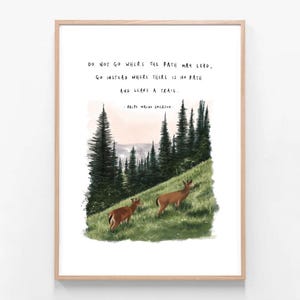 May include: A framed art print featuring a landscape scene with two deer grazing on a grassy hill. The artwork includes a forest of tall evergreen trees and a quote by Ralph Waldo Emerson: "Do not go where the path may lead, go instead where there is no path and leave a trail."