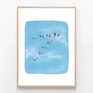May include: A framed art print showing a flock of geese flying in formation against a blue sky with white clouds. The geese are illustrated in brown, black, and white, creating a tranquil nature scene.