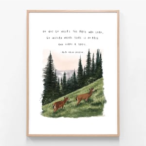 May include: A framed art print featuring a landscape scene with two deer grazing on a grassy hill. The artwork includes tall evergreen trees and a quote by Ralph Waldo Emerson: "Do not go where the path may lead, go instead where there is no path and leave a trail."
