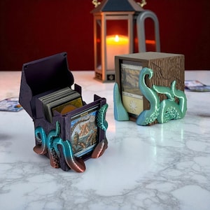 May include: Purple card storage box with an octopus design. The box is open, revealing a stack of cards. The octopus tentacles are teal and red. A second wooden box with a teal octopus design is also visible.