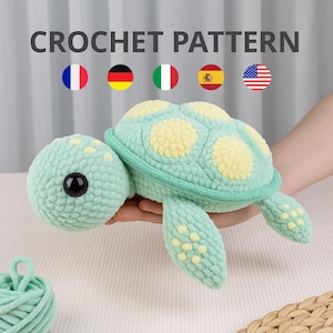 May include: A crocheted turtle in shades of mint green and yellow. The turtle has a round head with a large black eye and a shell with yellow spots. The text "CROCHET PATTERN" is displayed above the turtle.