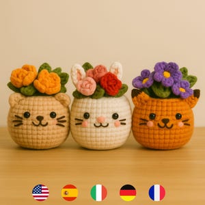 Può includere: Tre vasi per piante a forma di animale all'uncinetto, ognuno con un volto diverso e una composizione floreale sopra. I vasi sono beige, bianchi e arancioni, con fiori nelle tonalità dell'arancione, rosa, rosso e viola. Su una superficie di legno.