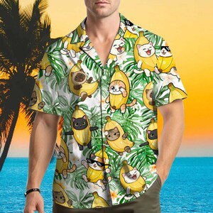 May include: Short-sleeved button-down shirt with a playful pattern of cats inside bananas and tropical leaves. The shirt features a white background with yellow, green, and brown accents. The shirt has a relaxed fit and a classic collar.