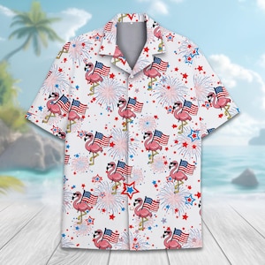 May include: White short-sleeved button-down shirt featuring a repeating pattern of pink flamingos wearing sunglasses and holding American flags. The design includes red, white, and blue fireworks and star shapes, creating a patriotic theme.