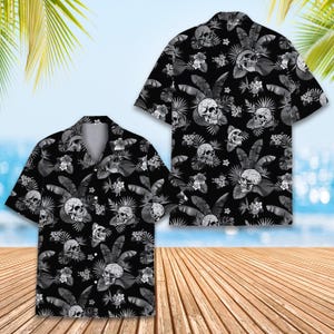 Peut inclure: Une chemise &agrave; manches courtes boutonn&eacute;e sur le devant, pr&eacute;sentant un fond noir avec un motif r&eacute;p&eacute;titif de cr&acirc;nes blancs, de feuilles de palmier tropicales et de fleurs d'hibiscus. Elle poss&egrave;de un col classique et un ourlet droit.