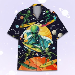 May include: Short-sleeved button-up shirt with a vibrant space-themed design. The shirt features green aliens surfing on yellow surfboards against a backdrop of planets, stars, and rockets. The shirt's color scheme includes navy blue, yellow, green, and orange.