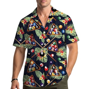 Könnte beinhalten: Kurzärmeliges Button-Down-Hemd mit dunkelblauem Hintergrund und einem sich wiederholenden Muster aus Billardkugeln, Holzdreiecken und Queues. Tropische Blumen und grüne Blätter sind im Design verstreut. Das Hemd hat einen klassischen Kragen und eine lockere Passform.