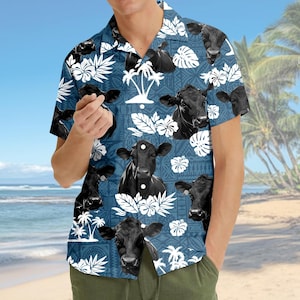 May include: A short-sleeved, button-down shirt with a blue background featuring a pattern of black cows, white tropical flowers, and palm trees. The shirt has a classic collar and is made of a lightweight fabric, perfect for warm weather.
