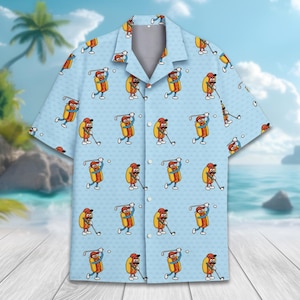 May include: A light blue button-up shirt with a pattern of cartoon hot dogs playing golf. The hot dogs are wearing sunglasses and have a red, white, and yellow color scheme.