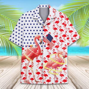 May include: Short-sleeved button-down shirt with a patriotic theme. One side features a pattern of blue stars on a white background. The other side has red flamingos and an American flag on a white background. The shirt is perfect for Independence Day.