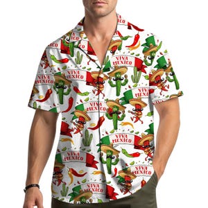 May include: White button-down shirt with a festive Mexican-themed pattern. The design features cartoon cacti wearing sombreros, playing guitars, and holding banners that read "Viva Mexico." Red chili peppers and green cacti are also included.