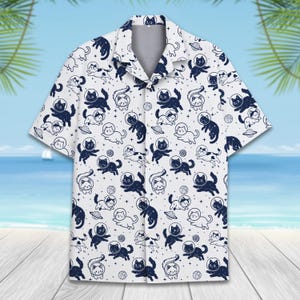May include: White short-sleeved button-up shirt with a repeating pattern of black cats in space. The cats are wearing astronaut helmets and are surrounded by stars.