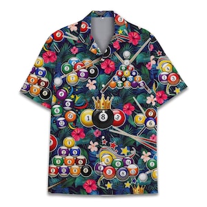 Könnte beinhalten: Ein kurzärmeliges Hemd mit einem lebendigen Druck von Billardkugeln, Queues und floralen Elementen. Das Design beinhaltet eine schwarze 8-Kugel mit einer goldenen Krone. Das Hemd hat einen dunkelblauen Hintergrund mit tropischen Blättern und Blumen.