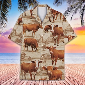 Puede incluir: Camisa abotonada de manga corta con un estampado repetido de vacas marrones, molinos de viento y granjas sobre un fondo beige. La camisa tiene un cuello clásico, perfecta para un look casual.