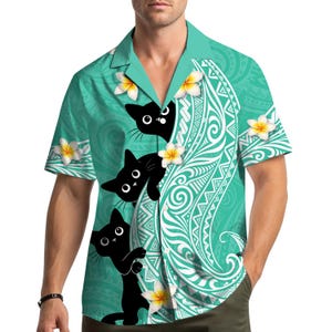 May include: A short-sleeved button-down shirt with a teal background and a white tribal pattern. The shirt features three black cat illustrations and yellow and white flower accents. The shirt is a casual, tropical style.