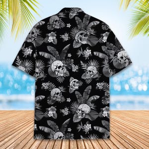 Peut inclure: Une chemise &agrave; manches courtes boutonn&eacute;e avec un fond noir orn&eacute; d'un motif r&eacute;p&eacute;titif de cr&acirc;nes blancs, de feuilles de palmier tropicales grises et de fleurs d'hibiscus blanches. La chemise pr&eacute;sente un col classique et un ourlet droit.