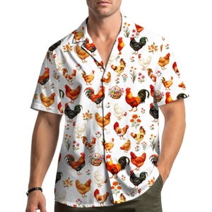 May include: White short-sleeved button-down shirt featuring a repeating pattern of colorful chickens, flowers, and floral baskets. The chickens are in various poses and colors, including red, brown, black, and white.