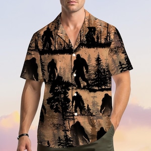 May include: Short-sleeved button-down shirt featuring a Bigfoot silhouette pattern in black against a brown and tan forest background. The shirt has a classic collar and is made of a lightweight fabric.
