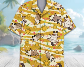 May include: Yellow short-sleeved button-down shirt with a repeating pattern of cartoon opossums, flowers, and stripes. The opossums are in various poses, and the flowers are yellow, pink, and white. The shirt has a classic collar and a relaxed fit.