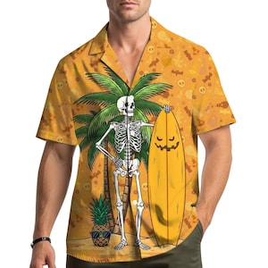 Puede incluir: Camisa naranja de manga corta con estampado de Halloween. La camisa presenta un esqueleto sosteniendo una tabla de surf amarilla con una cara de calabaza. Un árbol de palma y una piña con gafas de sol también están en el diseño.
