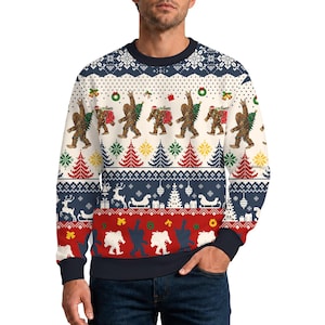 Peut inclure: Un sweat-shirt à col rond et manches longues arborant un motif festif avec des illustrations répétées de Bigfoot portant un sapin de Noël et un sac de cadeaux, alternant avec des sapins rouges et verts, des rennes et des traîneaux sur fond crème.