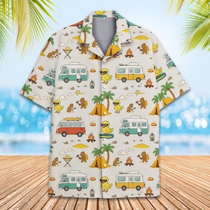May include: A white button-up shirt with a colorful pattern of camper vans, palm trees, yellow ducks, and campfires. The shirt has a relaxed fit and short sleeves.