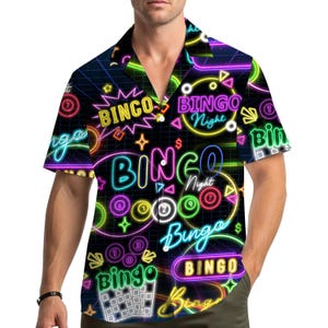 May include: Short-sleeved shirt with a black background and a neon bingo-themed design. The shirt features the words "BINGO Night" in various colours, along with bingo balls and other related graphics. The shirt is a vibrant and eye-catching piece.