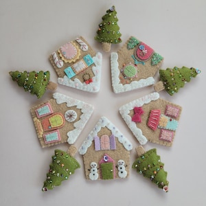 May include: Eight felt ornaments in the shape of gingerbread houses and Christmas trees. The houses are decorated with colorful details and glitter. The trees are green with white lights and beads.