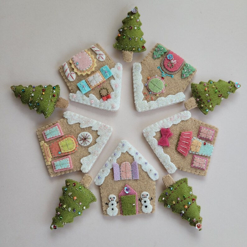May include: Eight felt ornaments in the shape of gingerbread houses and Christmas trees. The houses are decorated with colorful details and glitter. The trees are green with white lights and beads.