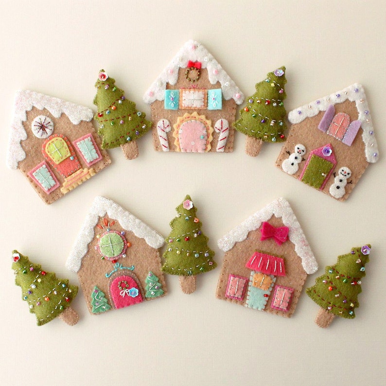 May include: Nine felt Christmas ornaments, including gingerbread houses and Christmas trees. The houses are decorated with candy canes, bows, and windows. The trees are green with white lights.