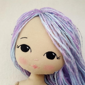 May include: A handmade doll with long, purple and blue yarn hair with silver accents. The doll has a stitched face with black eyes and pink cheeks.