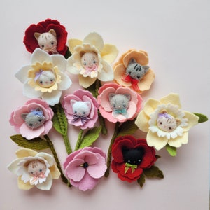 以下が含まれることがあります： 刺繍された猫が特徴のフェルトの花のブローチのコレクション。猫はそれぞれ異なる色の目と表情をしています。花は赤、ピンク、黄色、白など、さまざまな色があります。