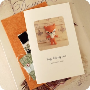 May include: A white card with the text "Tag-Along Fox a Gingermelon design" and a small orange fox with white accents in a square frame.
