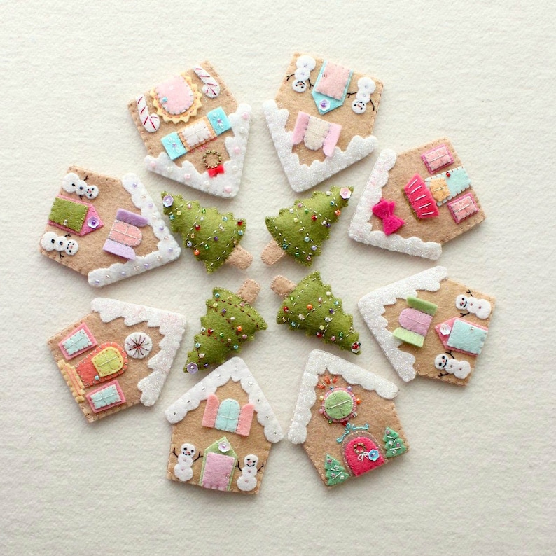 May include: A set of 10 felt Christmas ornaments, featuring gingerbread houses with snow-covered roofs, decorated with colorful details and small snowmen. The ornaments are arranged in a circle on a white background.