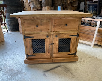 May include: A rustic wooden cabinet with two drawers and two doors. The doors have a metal grate design and black hinges. The cabinet is on wheels and has a distressed wood finish.
