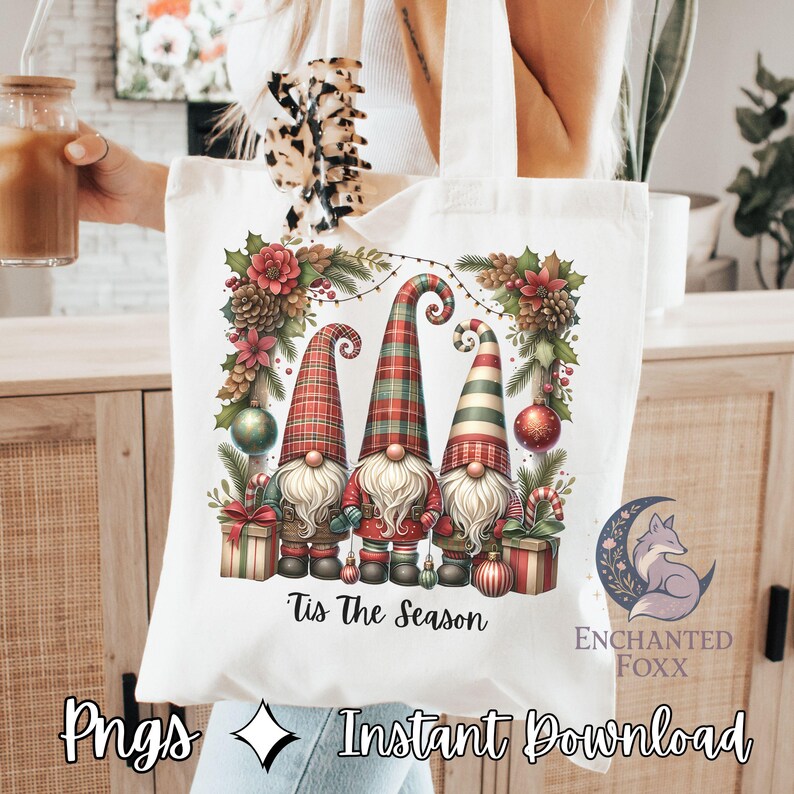 A white tote bag with a Christmas-themed graphic design featuring three gnomes surrounded by holiday decorations such as pine cones, berries, and ornaments.